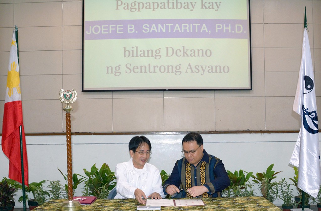 Chancellor Michael L. Tan (left) and Dean Joefe Sta. Rita (right) sign Dr. Sta. Rita’s appointment paper as AC dean at the Affirmation Rites at the GT-Toyota Asian Center Auditorium.