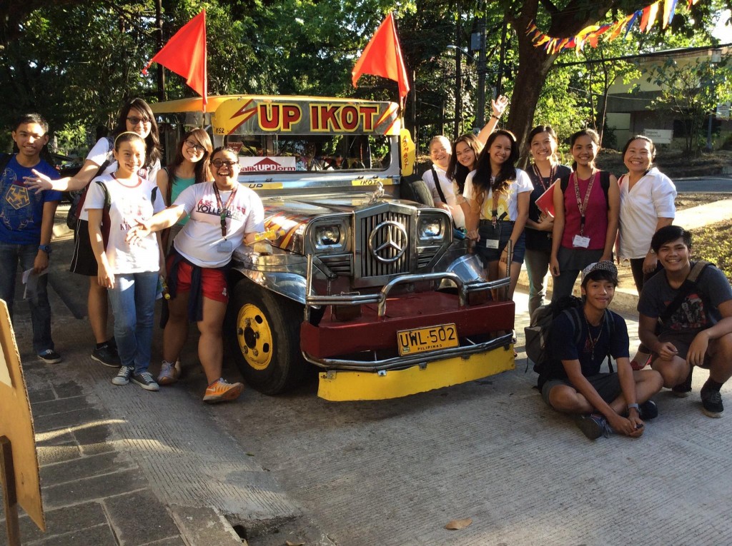 UPD student volunteers with former drom manager Alma Tiron beside an Ikot jeep used to visit the residence halls as part of "Tara, Tena Grand Launch and Fellowship."